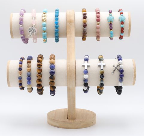 Bracelets en perles colorées, présentées sur un support en bois en forme de croix.